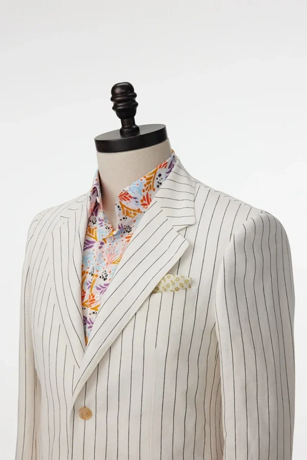 A suit jacket and shirt on display in a white room.