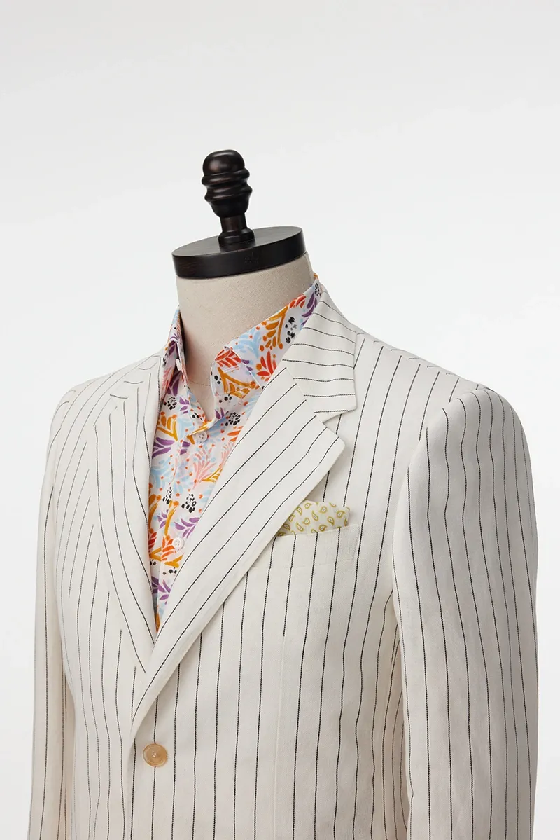 A suit jacket and shirt on display in a white room.