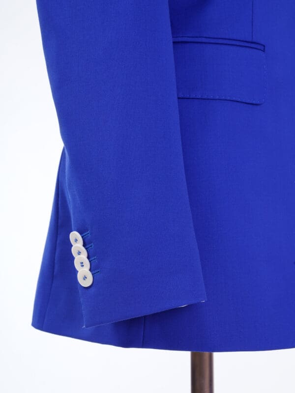 A close up of the sleeve and button on a blue jacket.